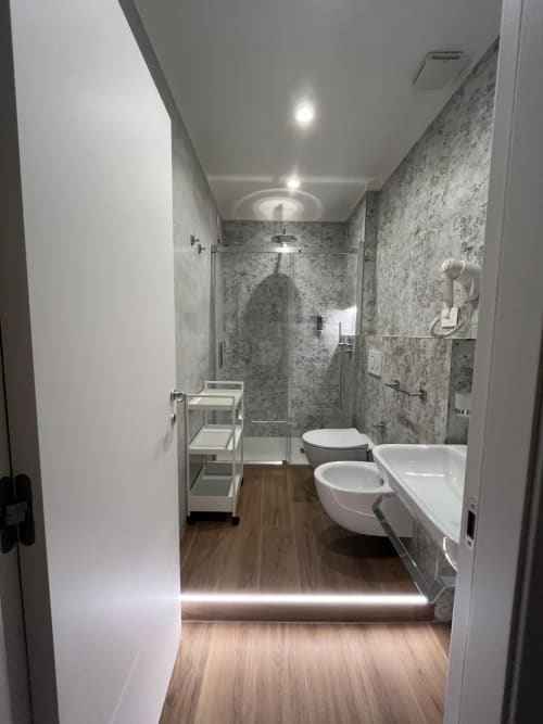 Bagno moderno a Maritza Guest House Roma con pareti in marmo, doppio lavabo, wc, bidet e doccia a pioggia