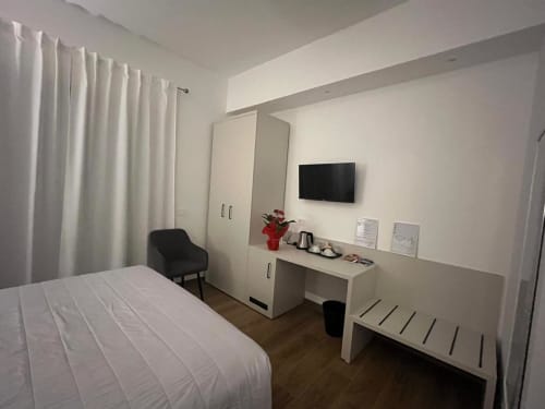 Camera moderna presso Maritza Guest House Roma con biancheria bianca, scrivania, TV, armadio e vista sulla città
