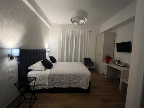 Camera moderna alla Maritza Guest House Roma con letto nero, biancheria bianca, TV a parete e vista sulla città