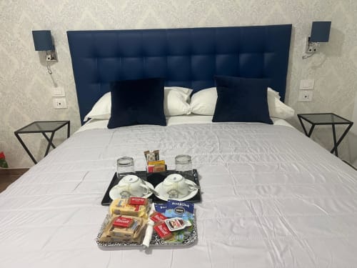 Camera Maritza Guest House Roma con testata blu navy, biancheria bianca, vassoio di benvenuto e vista sulla città
