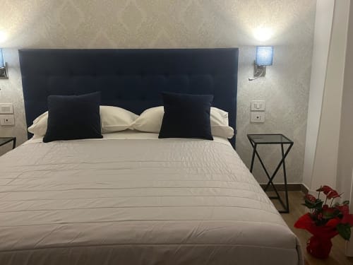 Camera moderna alla Maritza Guest House Roma con testata blu navy, biancheria bianca, cuscini neri e fiori rossi