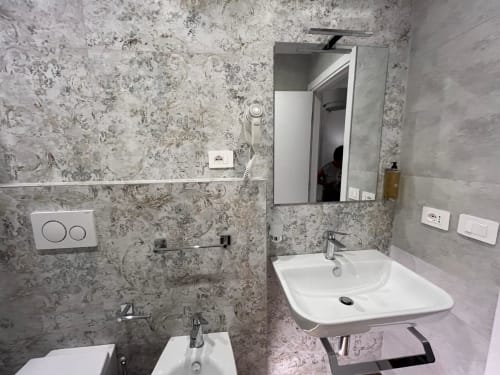Bagno moderno della Maritza Guest House Roma con doppi lavabi, specchiera e pareti rivestite in piastrelle decorative