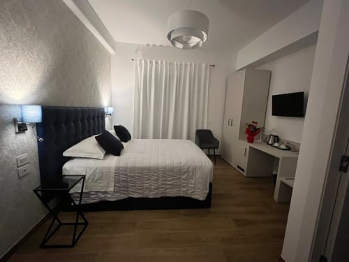 Camera moderna della Maritza Guest House a Roma con letto nero, biancheria bianca, TV a schermo piatto e vista sulla città