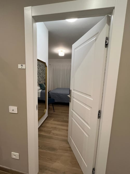 Camera 7 della Maritza Guest House a Roma con porta aperta che affaccia su camera da letto con specchio e letto