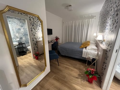 Camera moderna presso la Maritza Guest House Roma con letto, specchio, carta da parati decorata e vista sulla città