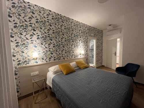 Camera moderna della Maritza Guest House a Roma con parete decorativa, letto matrimoniale, cuscini gialli e vista sulla città