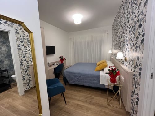 Camera moderna alla Maritza Guest House di Roma con carta da parati decorativa, letto blu e vista sulla città