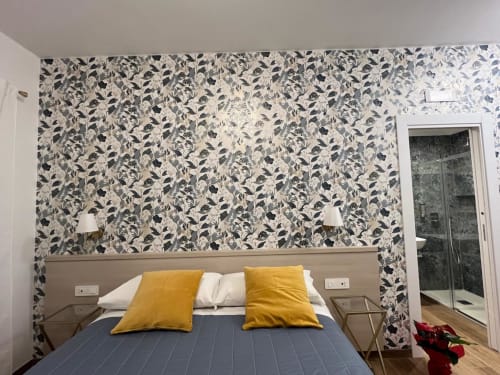Camera da letto della Maritza Guest House Roma con carta da parati a motivi di uccelli, cuscini gialli e armadio con specchio