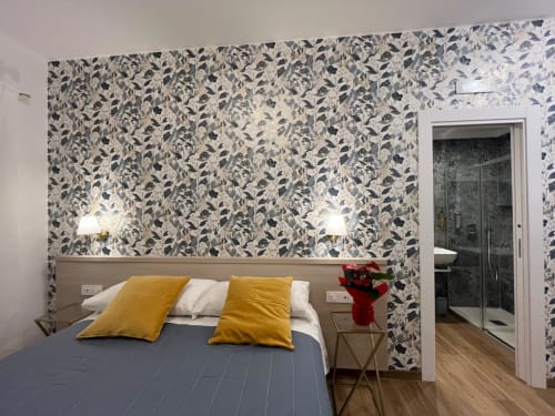 Camera della Maritza Guest House a Roma con carta da parati botanica, letto blu, cuscini dorati e bagno ensuite