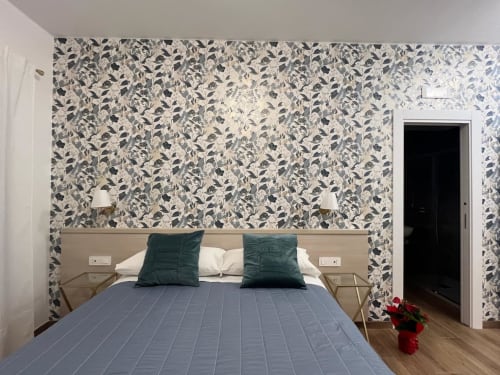 Camera moderna alla Maritza Guest House Roma con carta da parati decorativa, biancheria blu, cuscini teal e comodini in legno