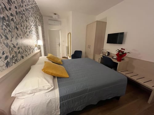Camera moderna alla Maritza Guest House di Roma con letto matrimoniale, cuscini gialli, vista sulla città e TV schermo piatto
