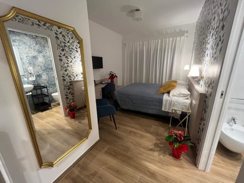 Camera moderna presso Maritza Guest House a Roma con letto, specchio dorato e bagno privato en-suite