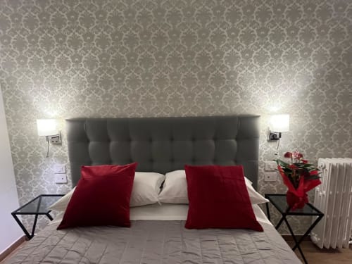 Camera moderna presso Maritza Guest House Roma con testata imbottita grigia, cuscini rossi e carta da parati damascata