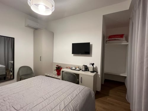 Camera moderna a Maritza Guest House a Roma con TV, scrivania, biancheria bianca e vista sulla città