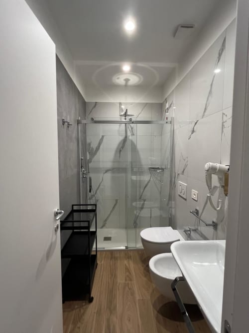 Bagno moderno alla Maritza Guest House Roma con doccia, WC, bidet e pavimento in legno