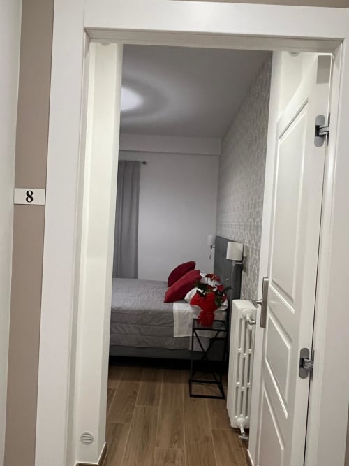 Camera 8 della Maritza Guest House a Roma, con letto dai cuscini rossi e vista sulla città attraverso la porta aperta