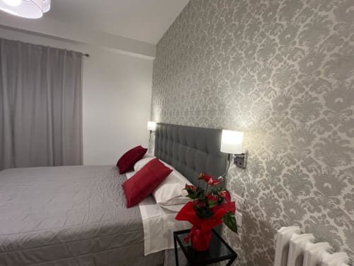 Camera moderna della Maritza Guest House Roma con carta da parati damascata grigia, accenti rossi e vista sulla città