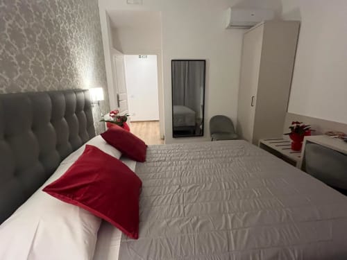 Camera moderna della Maritza Guest House Roma con letto imbottito grigio, cuscini rossi e vista sulla città