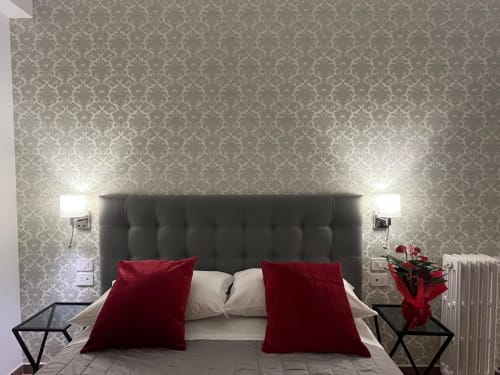 Camera elegante di Maritza Guest House Roma con carta da parati damascata, testata trapuntata, cuscini in velluto rosso e lampade comodino