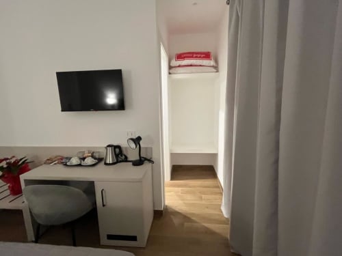 Camera moderna presso Maritza Guest House a Roma con TV a parete, scrivania di lavoro e accesso al corridoio