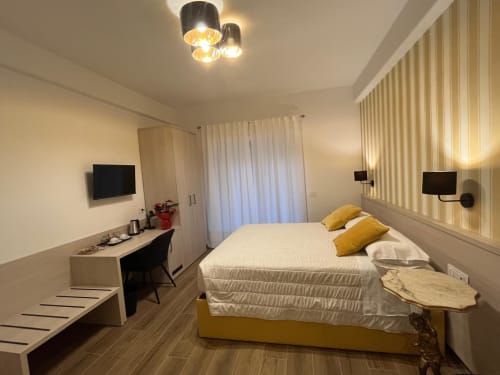 Camera moderna della Maritza Guest House a Roma con letto giallo, scrivania, TV e parete a righe