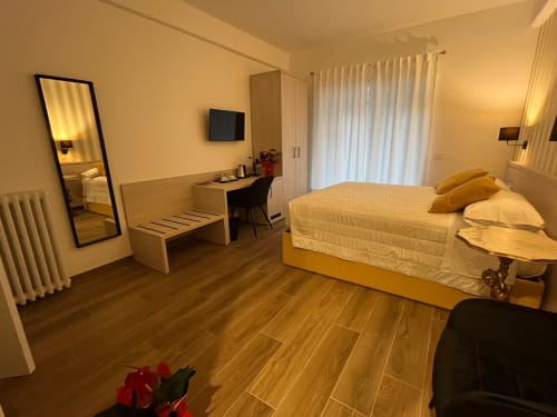 Camera moderna a Maritza Guest House Roma con accenti gialli, pavimenti in legno e vista sulla città