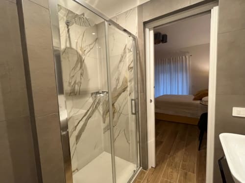 Bagno moderno con doccia in marmo, adiacente alla camera da letto presso la Maritza Guest House Roma