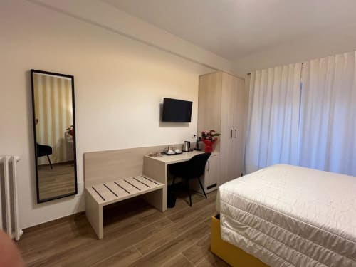 Camera moderna a Maritza Guest House a Roma con letto, scrivania, TV, specchio e vista sulla città
