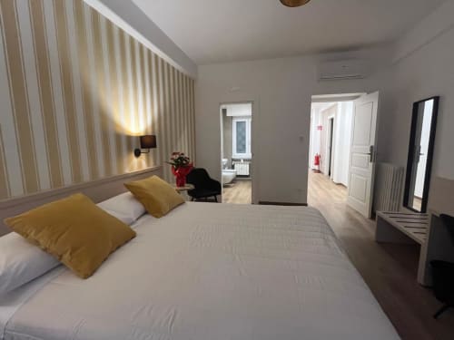 Camera moderna alla Maritza Guest House di Roma con vista sulla città, letto matrimoniale, cuscini dorati, parete a righe e bagno privato
