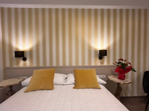 Camera moderna della Maritza Guest House a Roma con cuscini gialli, biancheria bianca e illuminazione d'atmosfera alle pareti