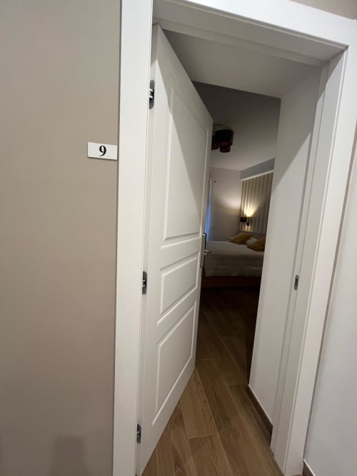 Corridoio della stanza 9 alla Maritza Guest House di Roma, con pavimenti in legno e porte bianche che conducono alla camera con vista sulla città