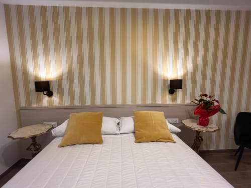 Camera elegante della Maritza Guest House Roma con cuscini gialli, biancheria bianca, carta da parati a righe e vista sulla città