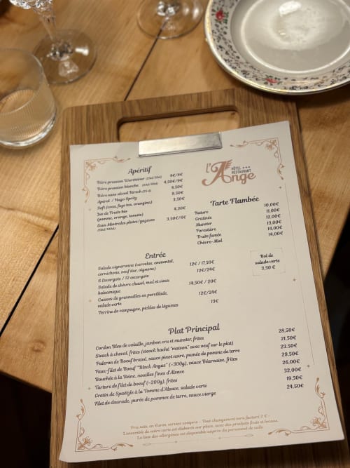Menu du restaurant L'Ange à Niedermorschwihr présentant apéritifs, entrées et plats principaux sur une table en bois