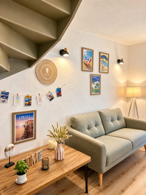 Salon moderne de la villa ALMA ROSSA en Corse avec canapé beige, table en bois, affiches de voyage corses et ambiance