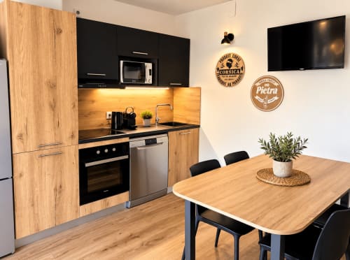 Cuisine moderne et salle à manger de la villa ALMA ROSSA à Lecci avec meubles en bois, appareils noirs et table de repas
