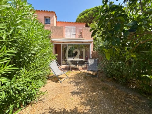 Villa en terre cuite à L'Île-Rousse avec patio ombragé, transats et verdure luxuriante près de la plage de Calvi