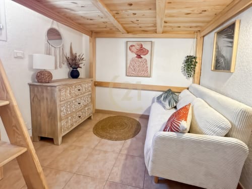 Spacieux séjour de villa avec poutres en bois, canapé blanc, commode décorée et œuvres côtières près de Calvi, L'Île-Rousse