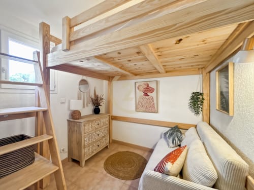 Chambre lumineuse de villa moderne avec poutres en bois, mezzanine, coin détente et décoration naturelle près de la plage de Calvi
