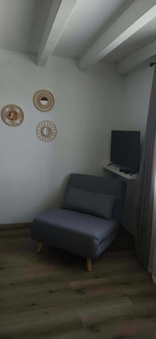 Chambre La Romantique à La Cour d'Arblade, avec fauteuil moderne, décoration murale et TV écran plat à Arblade-le-Haut