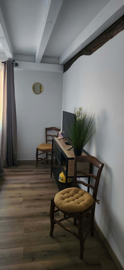 Chambre cosy de La Cour d'Arblade avec bureau en bois, chaises jaunes, plante en pot et poutres apparentes