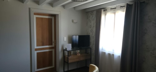 Chambre 3 du gîte La Cour d'Arblade avec TV, bureau, porte en bois et vue sur le jardin
