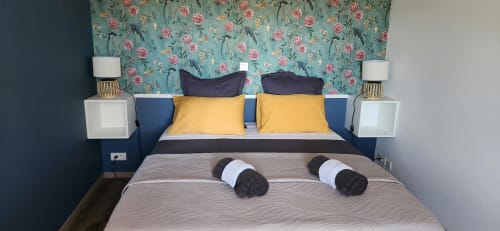 La chambre Romantique à La Cour d'Arblade B&B à Arblade-le-Haut avec papier peint fleuri, tête de lit bleue, oreillers jaunes et