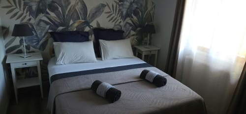 Chambre lumineuse à La Cour d'Arblade avec serviettes roulées, papier peint botanique, vue jardin et équipements modernes