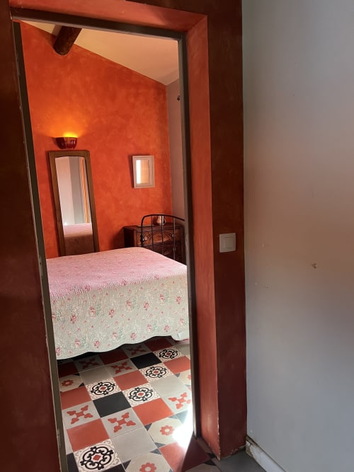 Camera da letto al Clos Bb di Saint-Cyr sur Mer con pareti arancioni vivaci, pavimento con piastrelle decorate e letto con coperta floreale