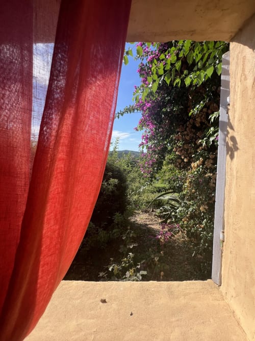 Tenda rossa che incornicia la vista su un lussureggiante giardino con buganvillea viola al Clos Bb, Saint-Cyr sur Mer