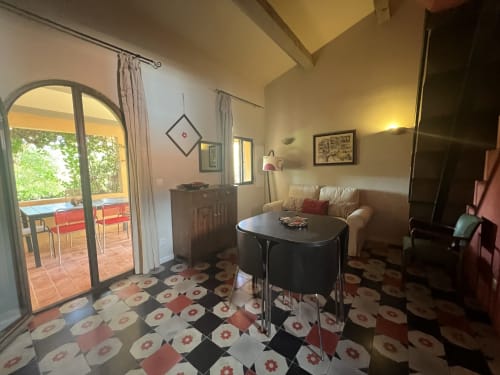 Lounge del Clos B&B a Saint-Cyr sur Mer con pavimento in piastrelle geometriche, tavolo nero, divano crema e accesso alla terrazza