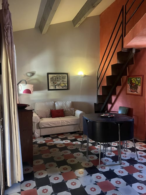 Salotto ospiti Clos B&B Saint-Cyr sur Mer con divano beige, tavolo rotondo nero e piastrelle geometriche