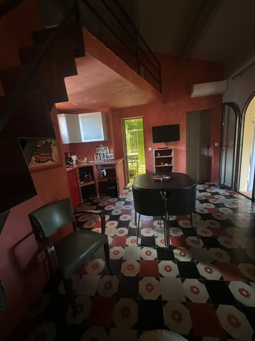Lounge Clos BB con pareti rosse, tavolo rotondo nero, pavimento decorato, Saint-Cyr-sur-Mer