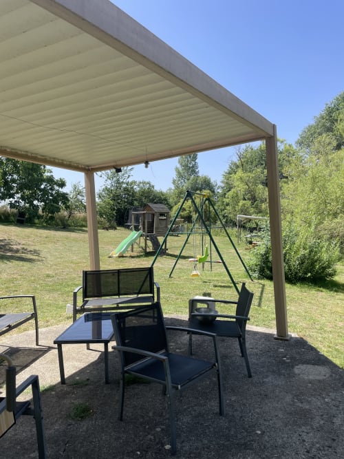 Terrasse extérieure ombragée du gîte Le Petit Moulin à Pouzauges, avec coin détente et aire de jeux pour enfants