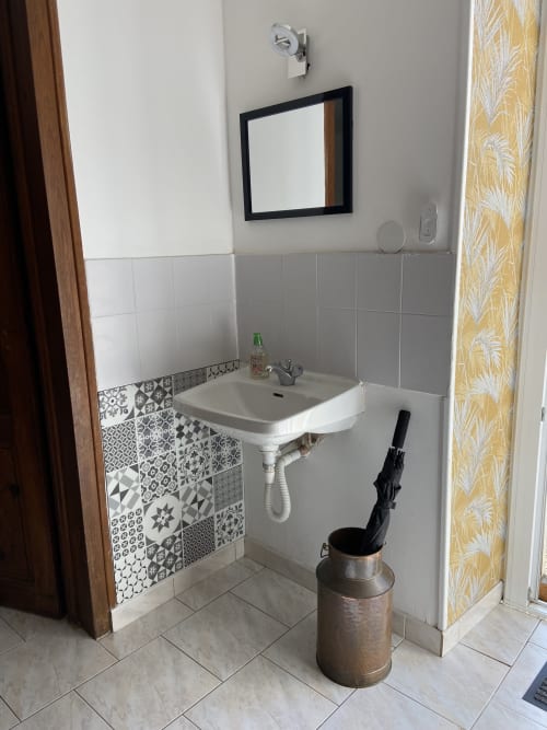 Lavabo de salle de bain orné de carrelage à motifs au gîte Le Petit Moulin à Pouzauges